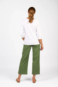 Woman wearing a white three-quarter sleeve tee and green wide-leg pants, rear view