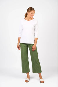 Woman in a white three-quarter sleeve tee and green wide-leg pants, standing, studio background