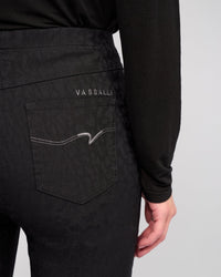 A close-up of a person wearing Vassalli Bay Pull On - Black pants, featuring animal-textured fabric, a pull-on style, and a back pocket with VASSALLI embroidery and white stitching.
